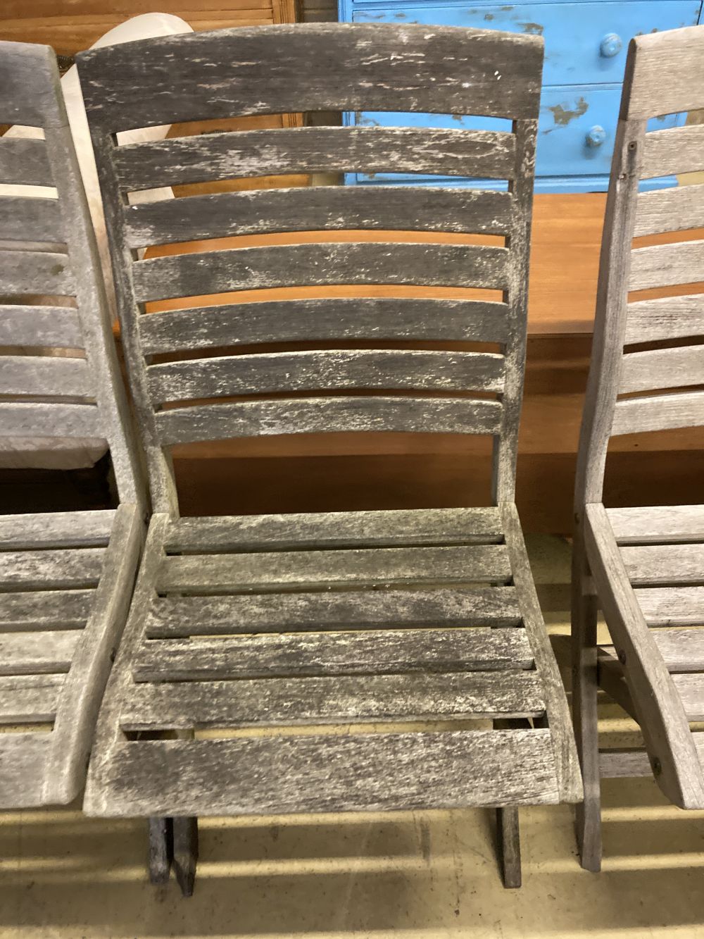 A set of four weathered teak folding garden chairs